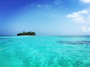 A stunning view of Ranguana Caye in Belize, surrounded by clear blue waters and set against a vibrant blue sky. A tropical oasis for the perfect Ranguana Caye Excursion experience.
