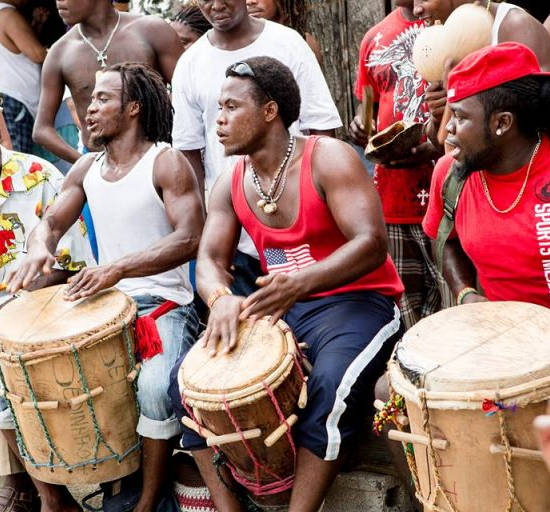 Group of Garifuna men passionately singing and drumming in unison.