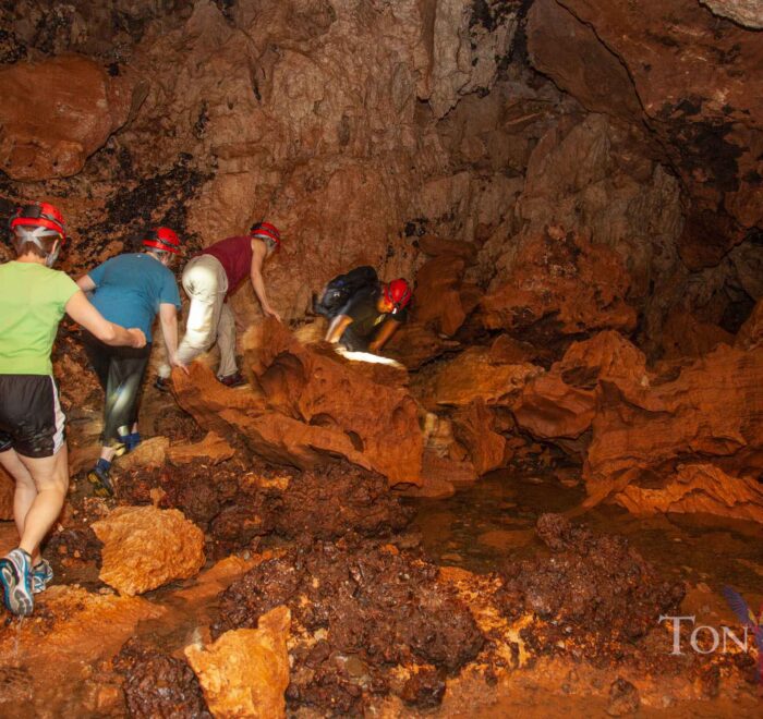 Group navigating rocky terrain inside ATM Cave.